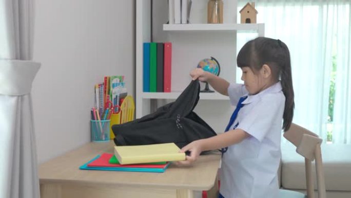 亚洲可爱的小学女生收拾书包，为开学第一天做准备。早上上学的日常生活准备上学。