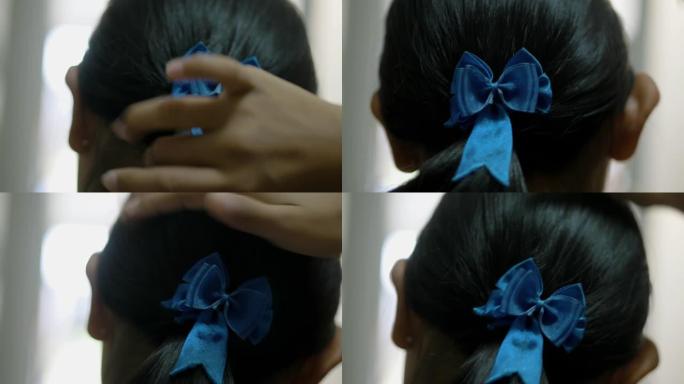 穿着制服的亚洲女学生在自己上学前梳头系好蝴蝶结，生活方式理念。