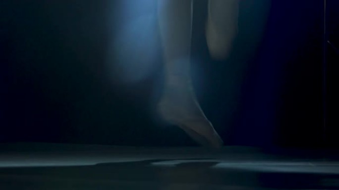 穿着脚尖鞋的芭蕾舞演员优美的腿。在工作室聚光灯背景下的黑暗中拍摄。芭蕾舞女演员展示经典芭蕾舞剧。特写