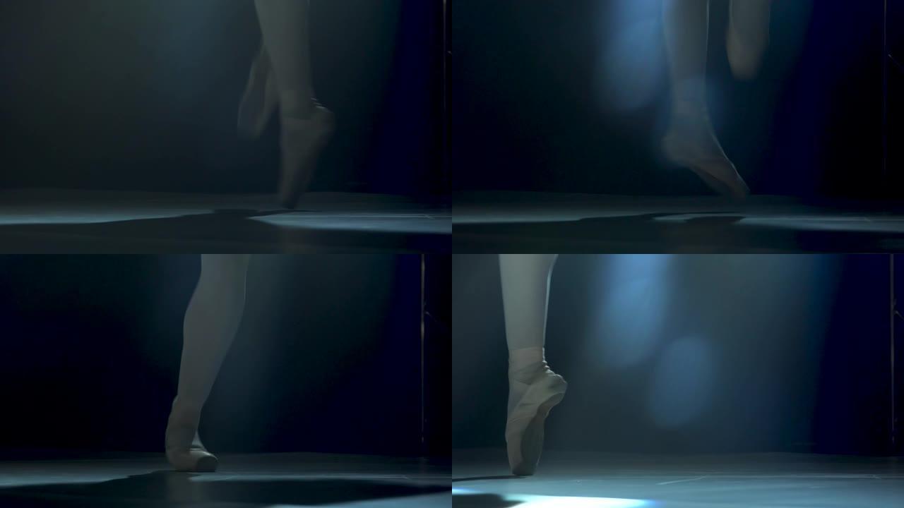 穿着脚尖鞋的芭蕾舞演员优美的腿。在工作室聚光灯背景下的黑暗中拍摄。芭蕾舞女演员展示经典芭蕾舞剧。特写