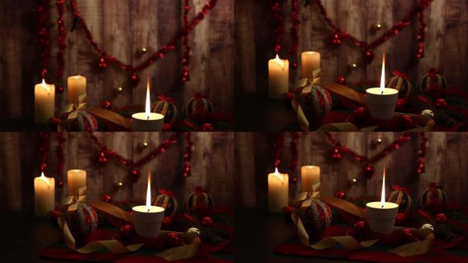 圣诞气氛: 一根蜡烛，前景有大火焰，红色和金色的小玩意，剪纸球，格子呢桌布上的缎面金丝带，木质背景从