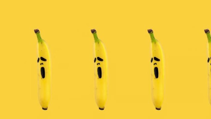 一排香蕉的无缝循环动画，上面画着黄色背景上可怕的恐惧面具。万圣节概念与复制空间