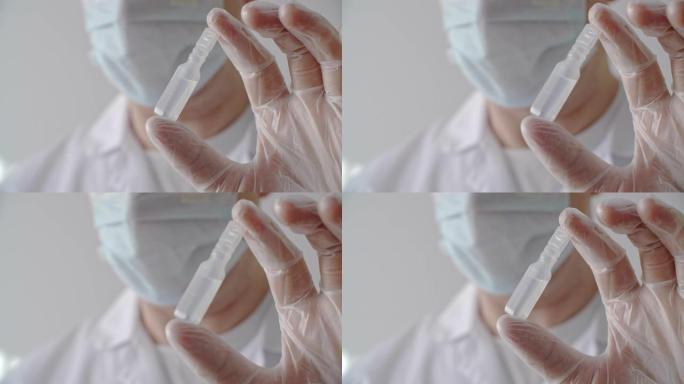 戴上医用手套，显示带有抗病毒疫苗的塑料安瓿。将安瓿与药液放在医生手中的防护手套中。停止电晕病毒概念。