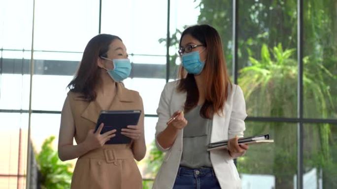 商界亚洲妇女走在一起戴口罩
