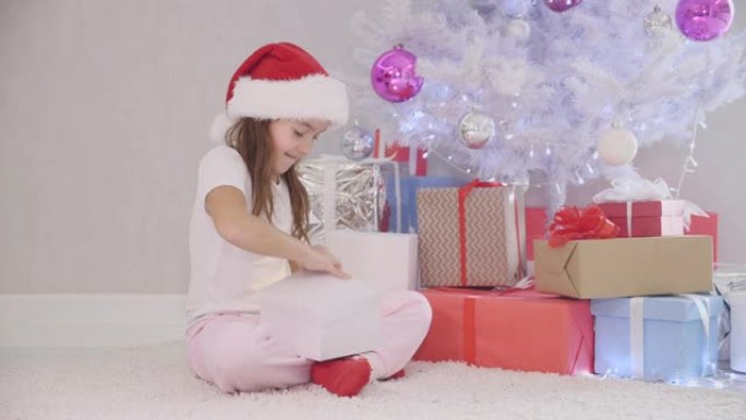 有趣的视频，晚上漂亮的孩子在圣诞树下放一个礼品盒。