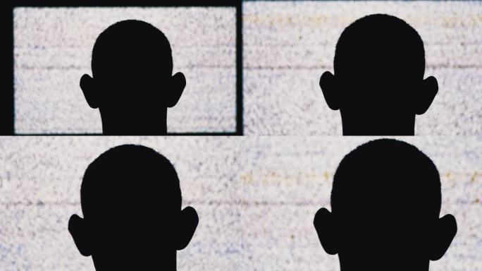 一名匿名男子头部的剪影正在观看白色静电噪音和电视干扰