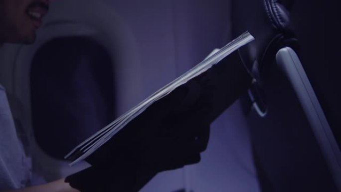 亚洲男子在飞机上阅读旅行书