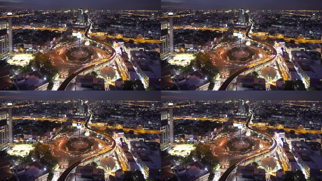 胜利纪念碑的鸟瞰图，在繁忙的街道上有车灯步道。曼谷市中心天际线的环形交叉路口。泰国。智慧城市金融区中