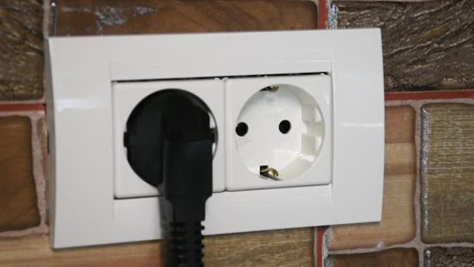 双电源插座。用男人的手连接和断开黑色电源插头。