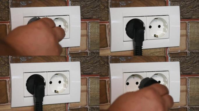 双电源插座。用男人的手连接和断开黑色电源插头。