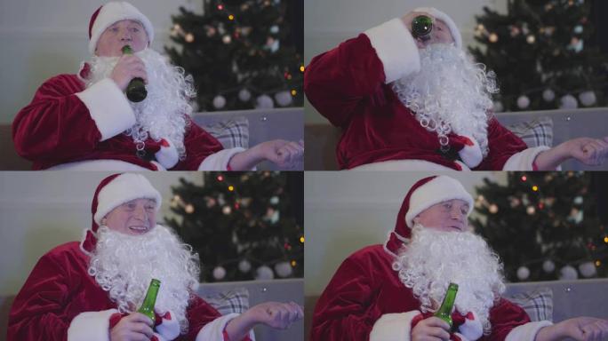 穿着圣诞老人服装的白人男子坐在沙发上喝啤酒的肖像。坏圣诞老人在室内休息。酗酒、抑郁、消极主义。