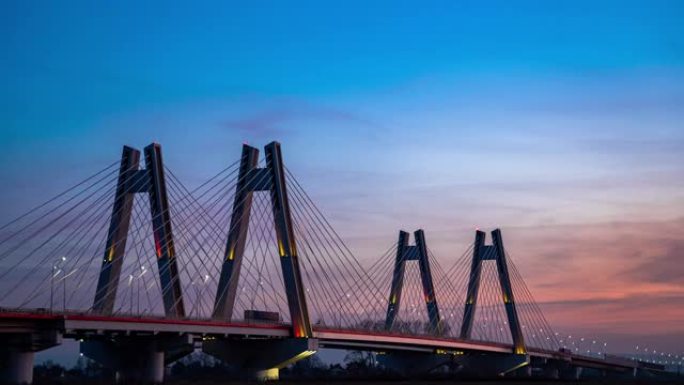 日落时，波兰克拉科夫维斯瓦河上具有纪念意义的，照明的新型现代双斜拉桥。过度，延时视频。