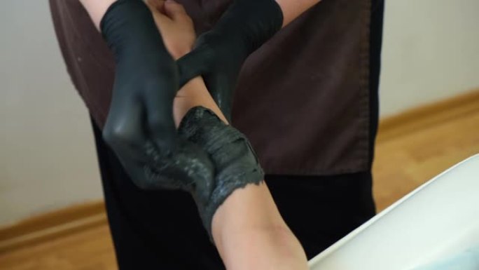 女人用黑色意大利面在腿上做糖的镜头。