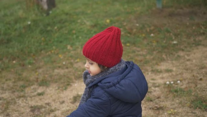 穿着蓝色夹克的男婴，红色针织帽子和灰色围巾