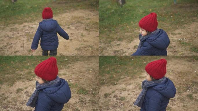 穿着蓝色夹克的男婴，红色针织帽子和灰色围巾