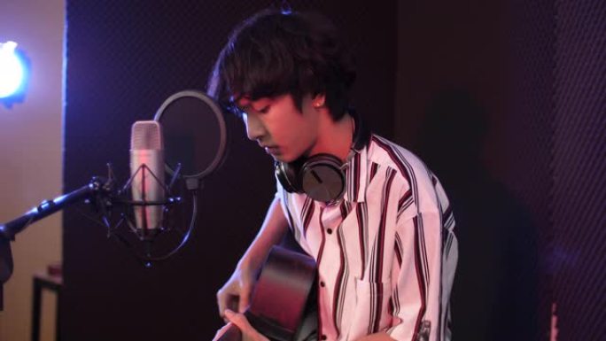 青年男歌手在录音室用吉他录制音乐，录音室概念