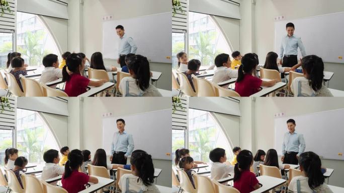 亚洲老师在学校的教室里教孩子。小男孩和女孩一起举手接受评论。教育、经验学习和技能发展的概念。