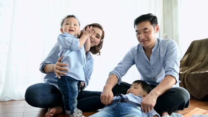 父母在家里的卧室里和两个半日本男孩玩耍。幸福的家庭和婴儿概念。多种族混血儿。欣赏父母身份和孩子。团结