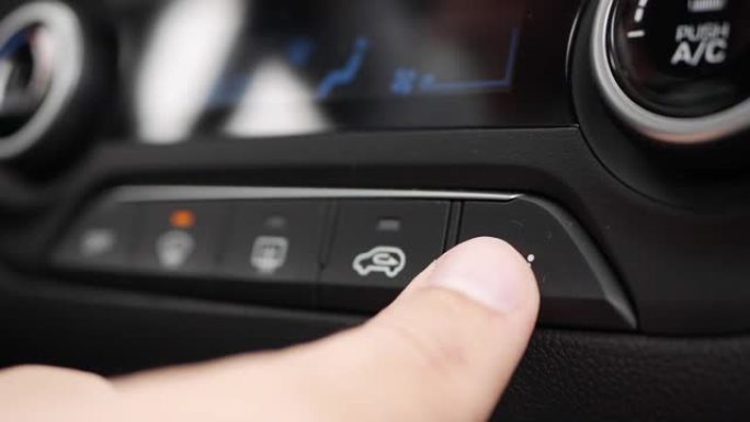 按下用于切换汽车空调运行模式的按钮的特写。男人的手转动按钮，调节车内的舒适性