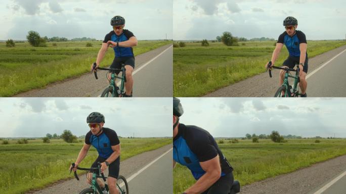 骑自行车的人正在查看健身追踪器上的训练数据。他开始提高骑行速度。骑自行车训练。背景中有一块绿色的田野