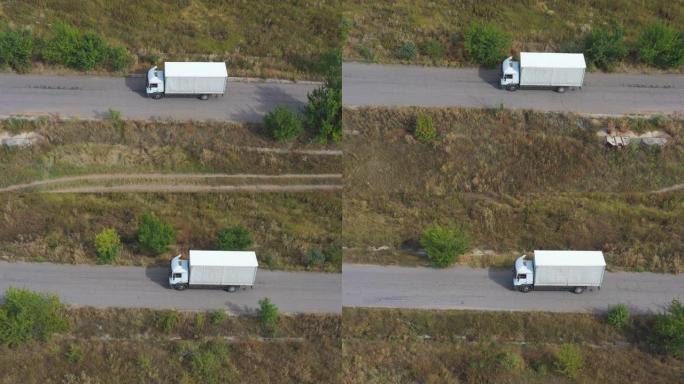 载货拖车在公路上行驶并运输货物的卡车的航拍。飞越送货卡车，沿着乡村的高速公路行驶。工业汽车骑行到目的