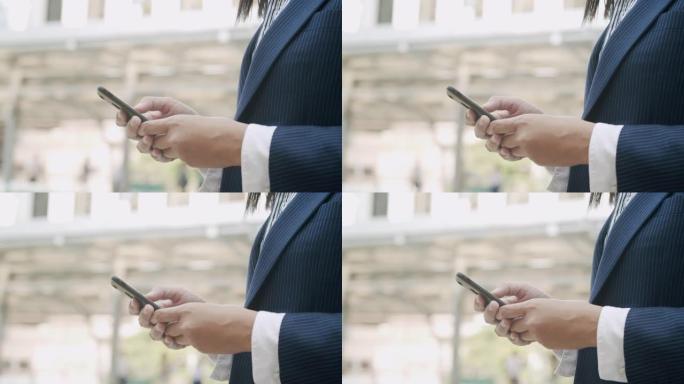 站在城市商业区时，年轻女商人的手触摸智能手机屏幕