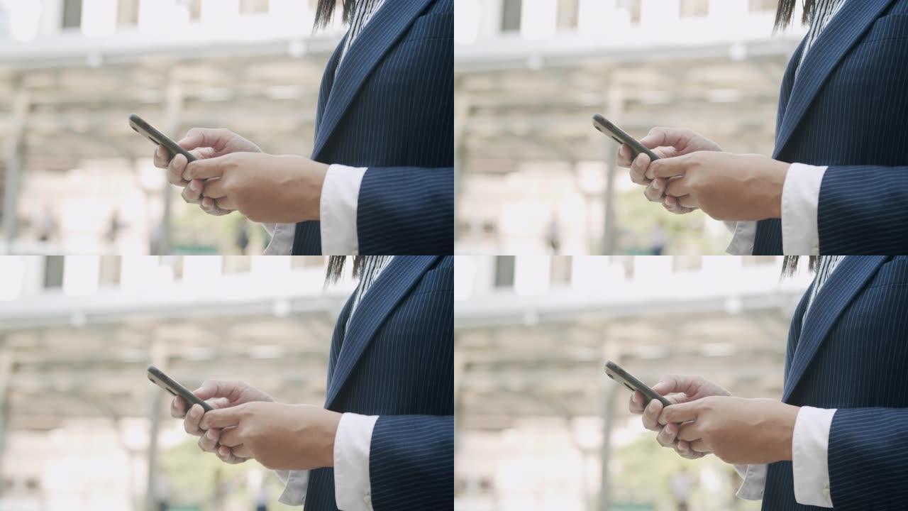站在城市商业区时，年轻女商人的手触摸智能手机屏幕