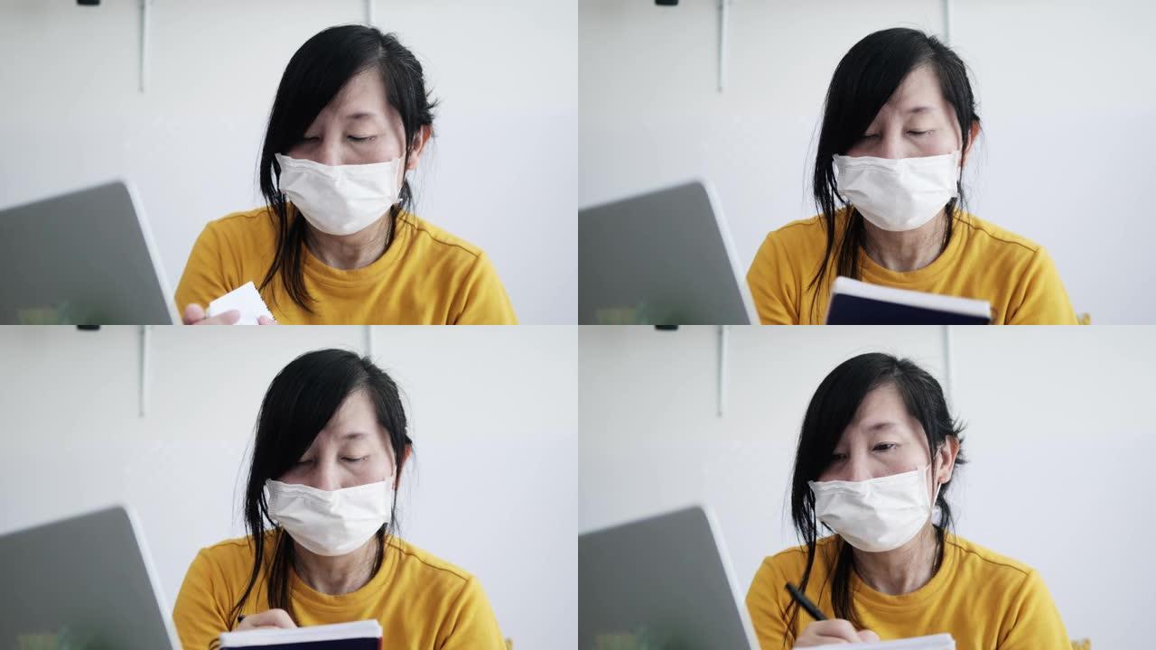 新型冠状病毒肺炎期间，亚洲女性在熨衣板上使用笔记本电脑或在家工作。