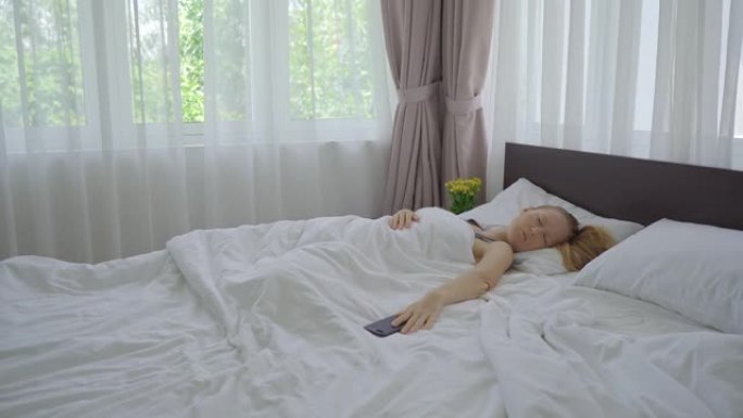 一个躺在床上的年轻女子。尽管手机上响起了闹钟，但她还是无法醒来