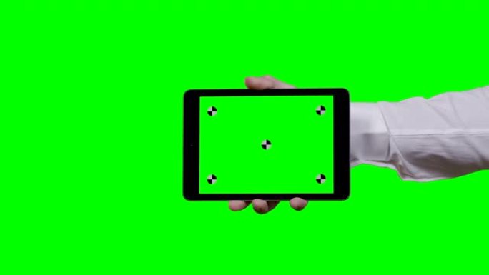 男人的手拿着平板电脑水平，绿色屏幕在前景和智能手机上的背景跟踪点从右侧进入屏幕屏幕