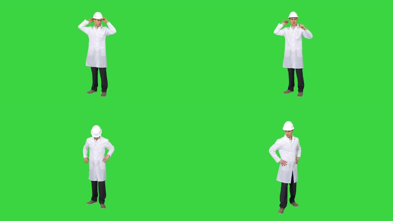 在绿色屏幕上工作后，戴着头盔跳舞的年轻工程师，色键