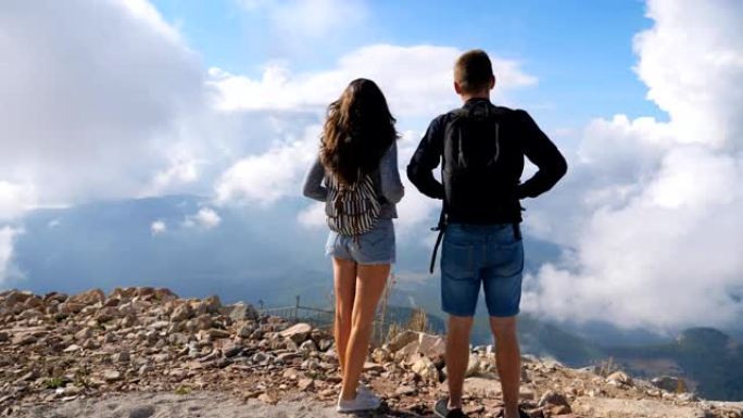 几个背着背包的徒步旅行者站在山边，享受风景。男人和女人在一起探索新地方的旅途中积极休息。美丽的背景。