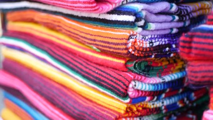 彩色墨西哥羊毛serape毛毯质地。编织装饰生动的纺织品，带有正宗的拉丁美洲图案。雨披和草帽的条纹多