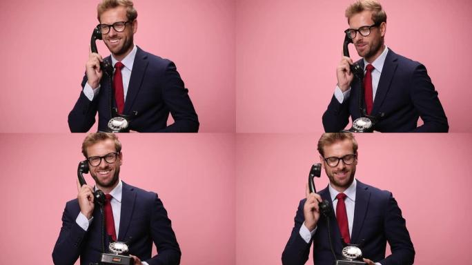快乐的年轻商人在电话上聊天，点头，同意并在粉红色背景上大笑