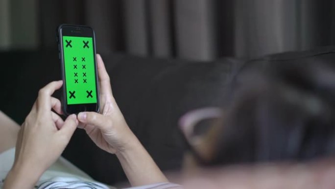 在客厅使用和看着智能手机绿屏的女人的手的2张照片