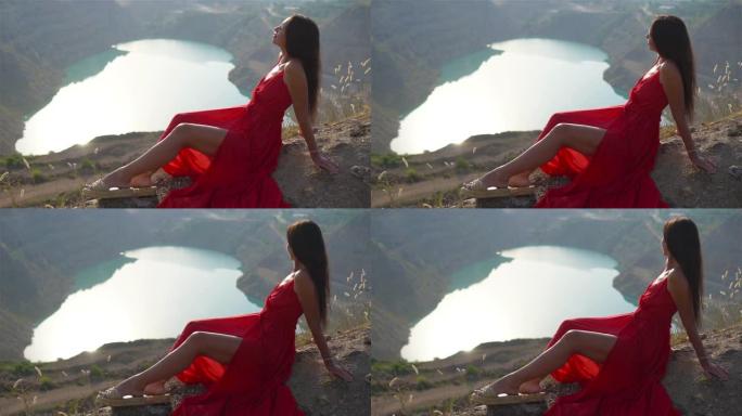 穿着红色连衣裙的女人像心一样站在湖边。欧洲度假的概念。美丽的风景