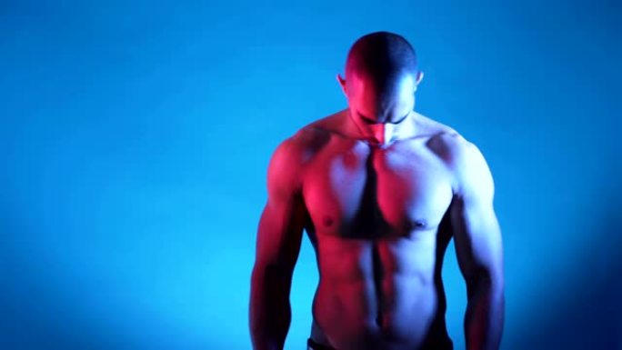 肌肉发达的健身男子躯干，六包摆姿势，在蓝色背景的工作室拍照