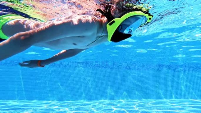 在游泳池里戴着面具潜水的孩子的水下视野。