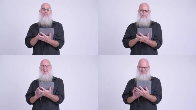快乐成熟的秃头大胡子男人使用数字平板电脑