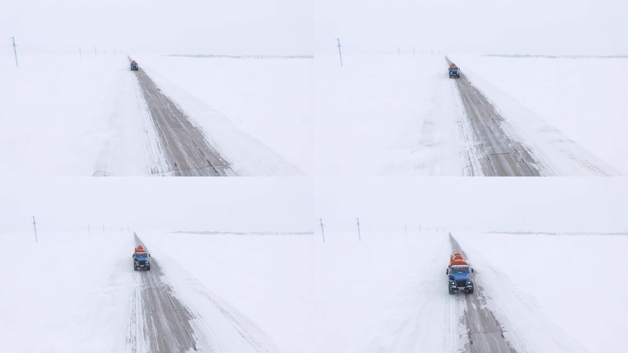 油罐车在积雪的田野中沿着空旷的道路行驶