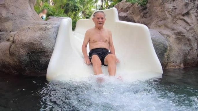 祖父在水上公园的水滑梯上滑行。