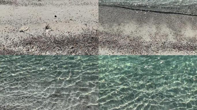 4k一个年轻的女孩进入清澈的翡翠海水，可以看到沙质的底部，整齐的色调和爱琴海的颜色。美丽纯净的自然镜