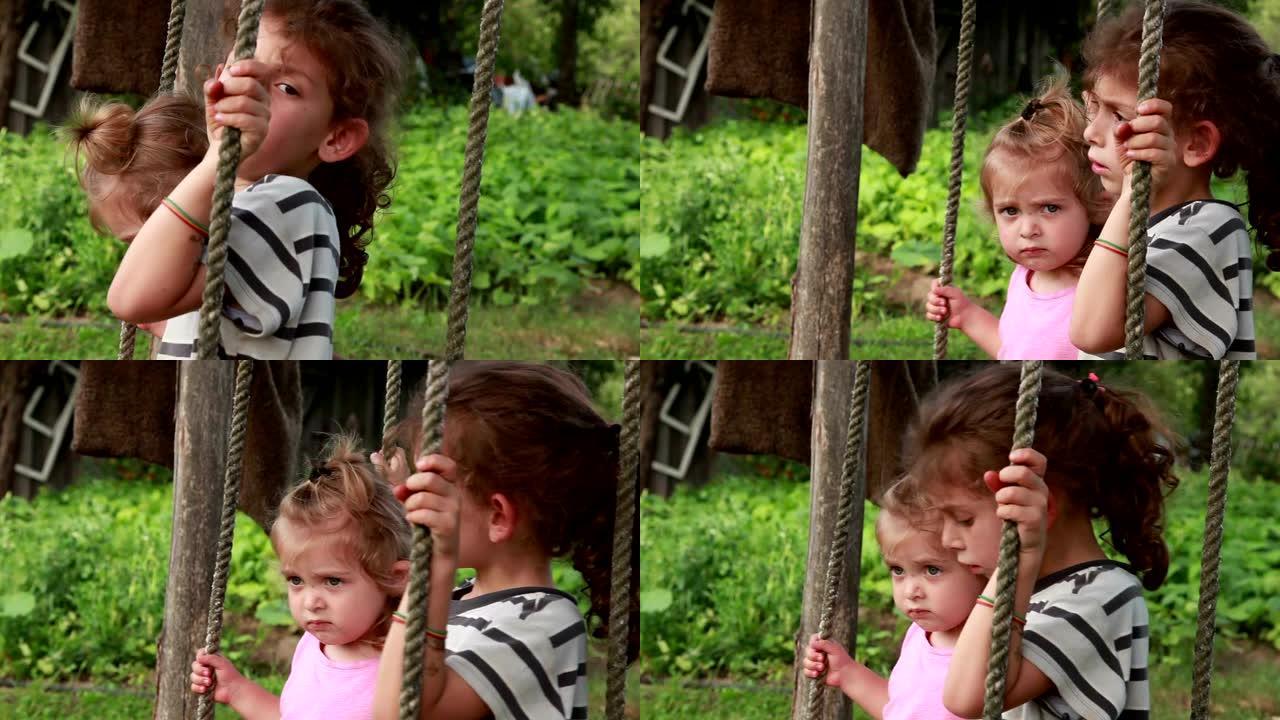 两个伤心的小女孩坐在后院的绳上荡秋千