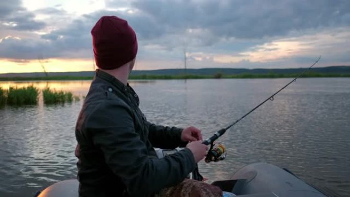 一名男子在日落时从船上在湖上钓鱼