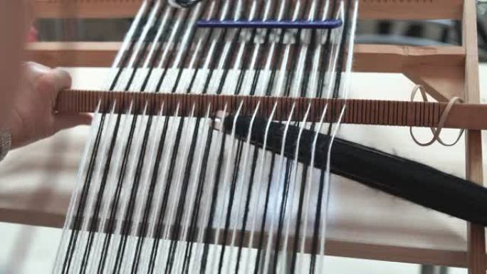 用传统编织机编织女人手的特写。家用织机。羊毛特写传统复古手工织布机的细节。传统的旧织机。