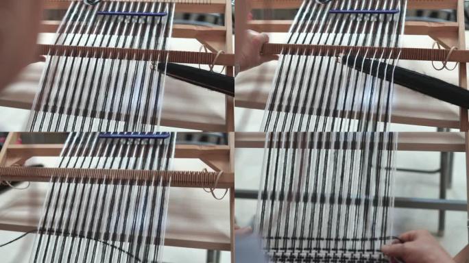 用传统编织机编织女人手的特写。家用织机。羊毛特写传统复古手工织布机的细节。传统的旧织机。