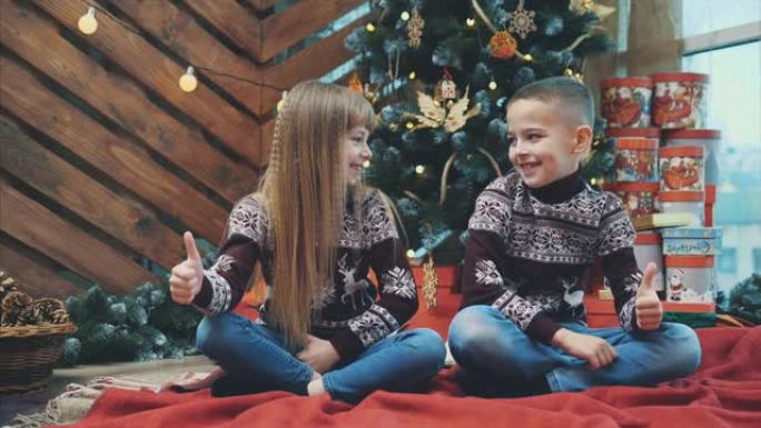 穿着深红色羊毛衫的高加索兄弟姐妹竖起大拇指，对新年气氛感到满意。