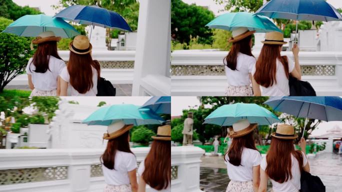 泰国日本同胞的女导游参观该国的主要景点。泰国曼谷的 “Wat Pho” 地标。两名亚洲妇女在雨天撑伞