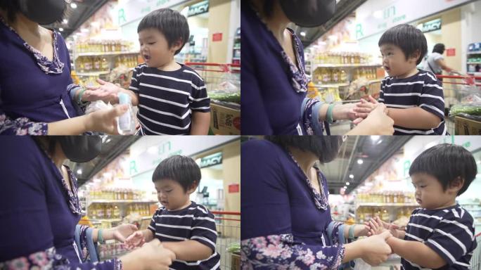 亚洲母亲在超市吃饭前用洗手液凝胶给儿子