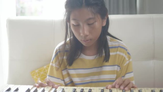快乐的亚洲女孩在家练习键盘乐器技能，生活方式理念。